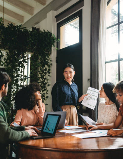 Business meeting of young adult people in a modern loft. A woman leader is talking about the new strategies of the business.