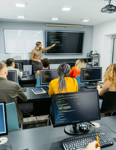 Young male teacher teaching young students a programming class in the classroom.